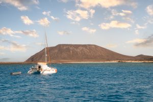 White catamaran sailing on calm sea against mountain - Luxury Yacht Rental Cancun